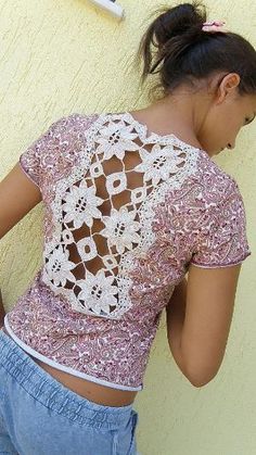 a woman leaning against a wall with her back to the camera and wearing a pink top