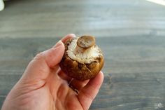 a hand holding a mushroom on top of a wooden table