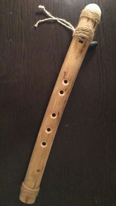 a wooden recorder with two holes in the middle and string attached to it's body