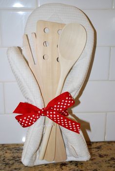 wooden utensils with red polka dot bows are stacked on top of each other