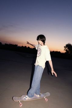 a young man riding a skateboard on top of cement ground at dusk with the sun setting in the background