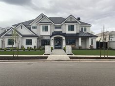 a large white house with lots of windows and grass in front of it on a cloudy day