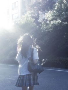 a girl in a skirt is standing on the street