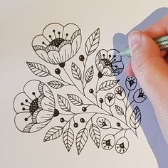 someone is drawing flowers on a piece of paper