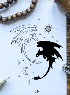 a paper with a drawing of a dragon on it next to some beads and a pen