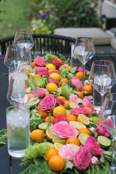 the table is set with flowers, oranges and wine glasses on top of it