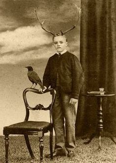 a young boy standing next to a chair with a bird on it's head