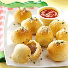 several small rolls on a white plate with dipping sauce in the bowl next to them