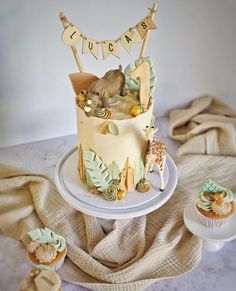 there is a cake with animals on it and some cupcakes next to it