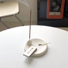 a white table topped with a book and two small sticks sticking out of the top