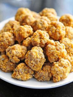 a white plate topped with mini meatballs on top of a black countertop next to a cup of coffee