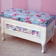 a white bench with pink flowers on it in front of a pink and blue striped wall