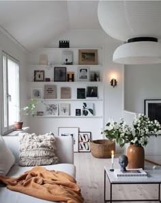 a living room filled with white furniture and lots of pictures on the wall above it