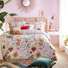 a bedroom with pink walls and colorful bedding in the center is a large plant