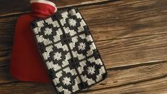 a black and white cell phone case sitting on top of a wooden table next to a red bag