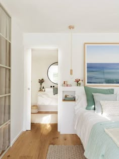 a bedroom with white walls and wood flooring next to a bed in front of a window