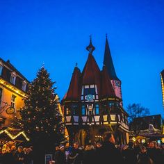 a christmas tree is lit up in front of an old - fashioned building