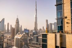 a woman standing on top of a building looking out at the city skyline in dubai