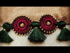 a red and green brooch with tassels on it's back end