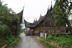 an old wooden building sitting on the side of a road next to lush green trees