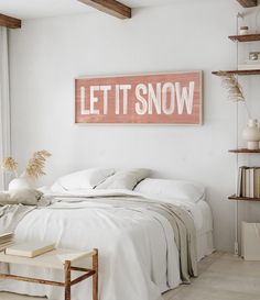 a bedroom with white walls and a wooden sign that says let it snow