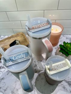 three toothbrush holders sitting next to each other on a marble counter top in front of a tiled wall