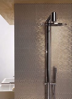 a shower head in the middle of a tiled wall with an exposed faucet