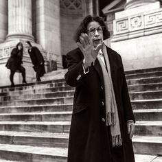 an old woman standing in front of some steps with her hand up to her face