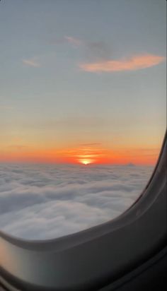 the sun is setting over some clouds from an airplane window