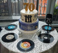 a cake with the number 70 on it surrounded by vinyl records and wine glass holders