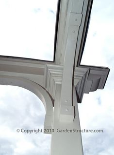 the corner of a white building with an open window and sky in the back ground