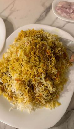 a white plate topped with rice and other food on top of a marble countertop