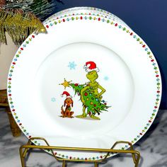 a plate with the grinch on it is sitting on a rack next to a christmas tree