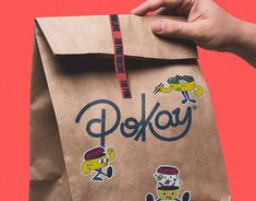 a person holding a brown paper bag with stickers on it that says pekoy