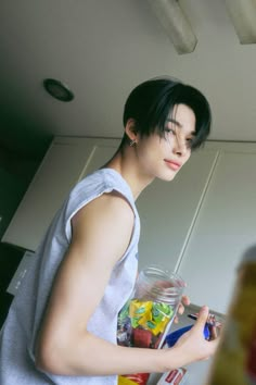 a woman standing in a kitchen next to a jar filled with fruit and veggies