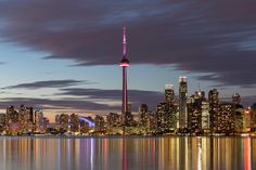 the skyline of toronto is reflected in the water at night, as seen from across the bay