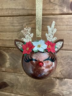 a christmas ornament hanging on a wooden wall with reindeer antlers and poinsettis