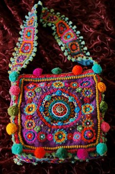 a multicolored purse with pom poms hanging from it's side