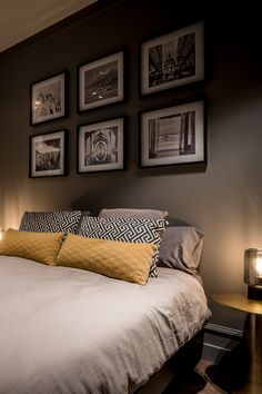 a bedroom with pictures on the wall above the bed and below the bed is a night stand