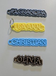 three different colored plastic name tags on a white surface with the word grandma written in black