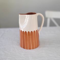 a white and brown vase sitting on top of a table