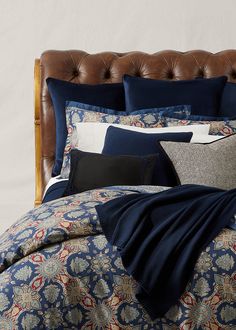 a bed covered in blue and white comforter next to a brown leather headboard