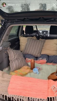 the trunk of a car with pillows and blankets in it