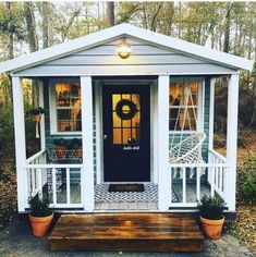 a small white house with a porch and steps leading up to the front door that has a wreath on it