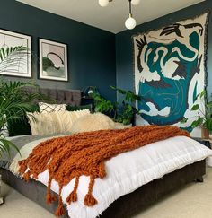 a bedroom with blue walls and white bedding, plants on the side of the bed