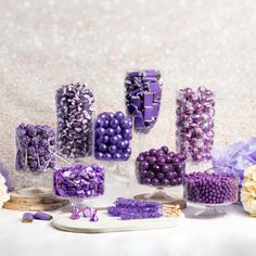 there are many different types of candies on the table with purple and white decorations