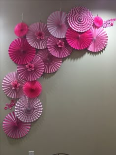 several pink paper umbrellas hanging on the wall