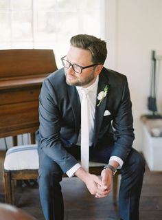 a man in a suit sitting on a chair next to a piano