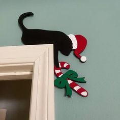 a black cat with a santa hat and candy canes hanging on the wall