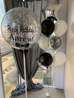 balloons and streamers in front of a window with the words happy birthday written on them